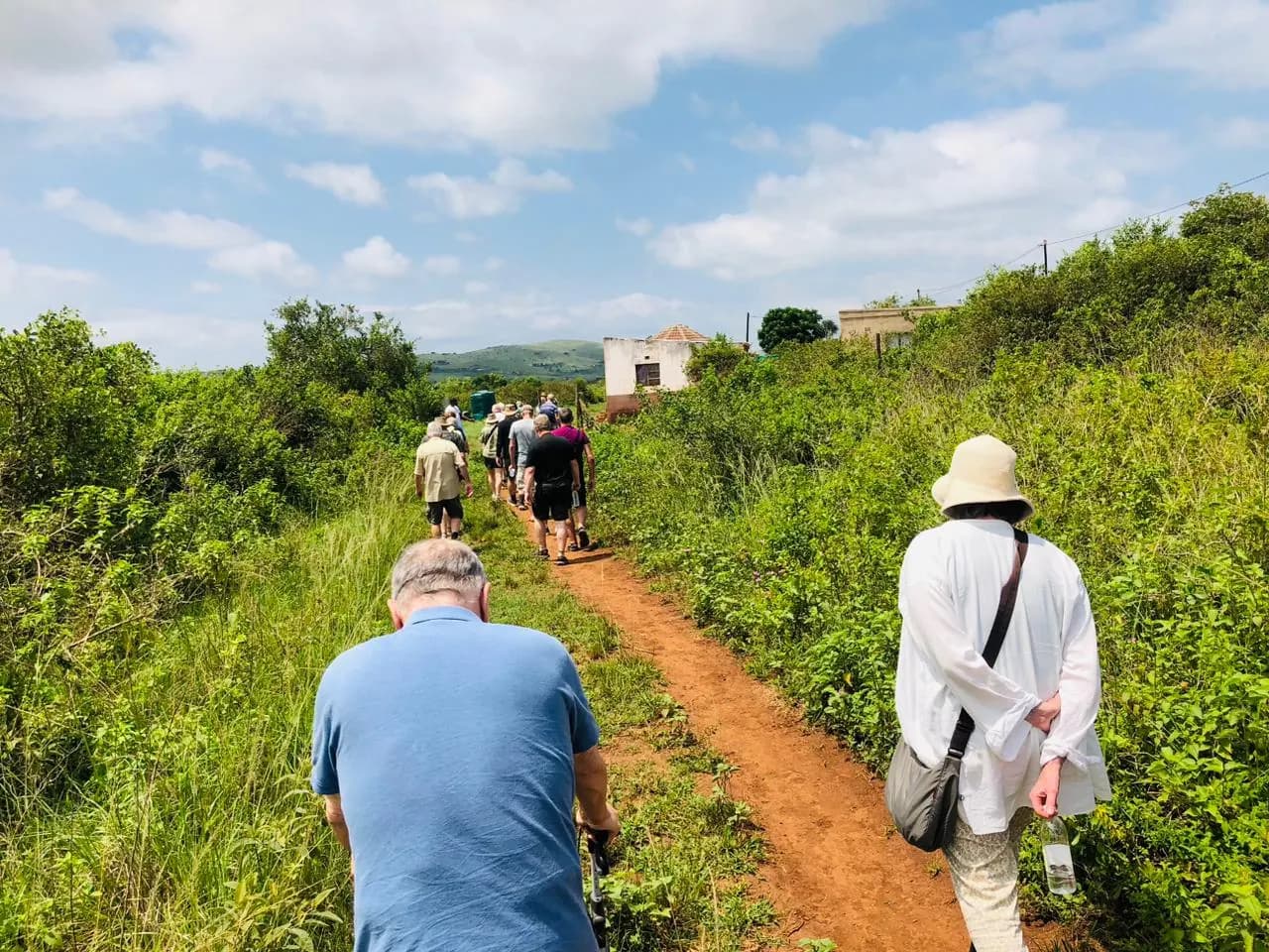 Guests walking a red-earth footpath towards the hills near Macabuzela village, Hluhluwe